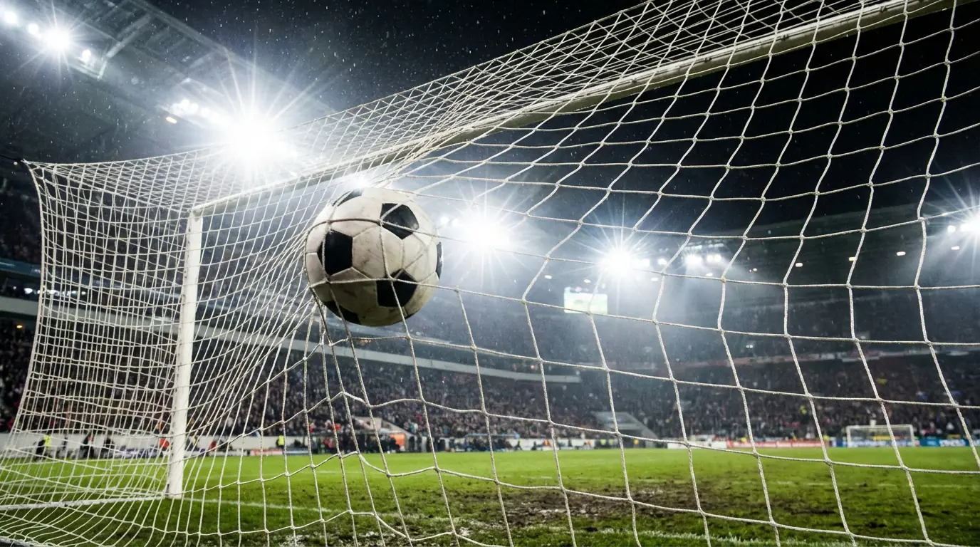 Pallone da calcio che entra nella rete di una porta durante una partita serale allo stadio